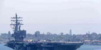 Aircraft carrier escorted by a tugboat in a harbor
