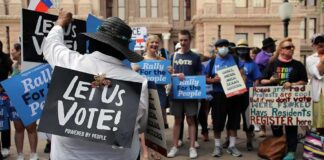 Protesters holding signs at a voting rights rally