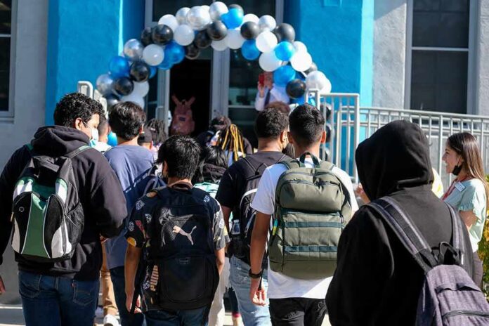 Students with backpacks enter a school under a balloon arch