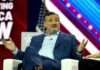 U.S. Senator Is Worse Than a Neo-Nazi Influencer man in blue suit speaking on stage