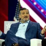 U.S. Senator Is Worse Than a Neo-Nazi Influencer man in blue suit speaking on stage
