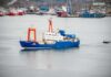 One Giant Shark. One Old Nuclear Mystery. Blue research vessel in harbor with orange cranes
