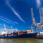Putin Threatens to Seize European Ships Container ship docked at port with cranes loading cargo