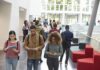 Trust Crash Hits Colleges Again Students walking through a bright campus atrium using mobile devices