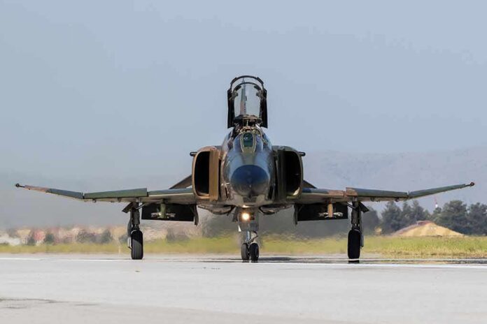 Military jet taxiing on runway with open canopy