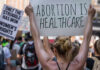 Icon Down: Women’s Rights Pioneer Dies at 92 Protestors holding signs about womens rights and healthcare.