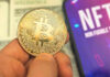 Trump Reports $1.4B in Crypto Income Person holding Bitcoin coin, NFT text on screen.