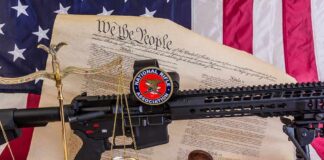 Rifle with NRA badge on Constitution backdrop with scales and gavel