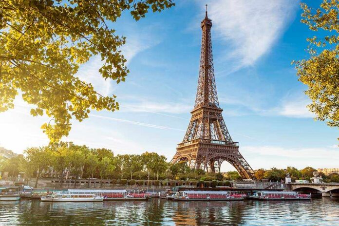 Eiffel Tower in Paris with boats on the river and green trees