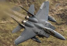 Fighter jet banking low over rugged terrain