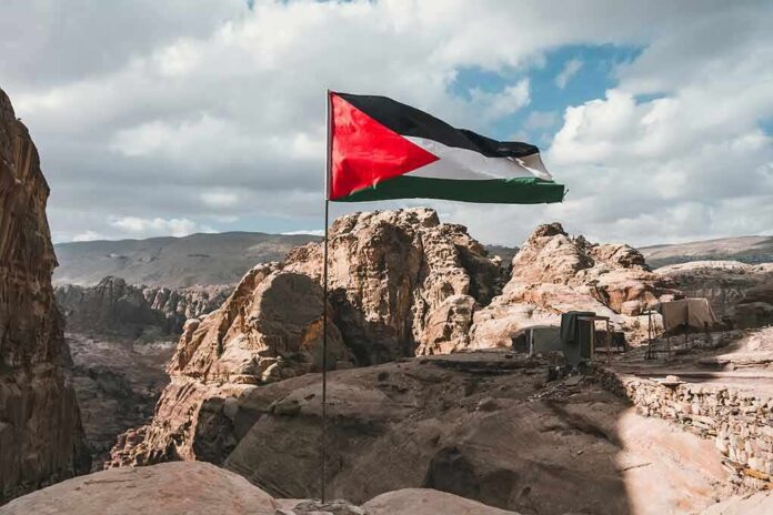 shutterstock_1260266692 Palestinian flag waving over rocky desert cliffs