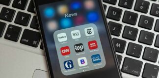 Smartphone displaying a folder of news apps on a laptop keyboard