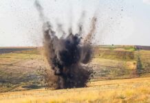 Explosion sending dark smoke and debris into the air in an open field