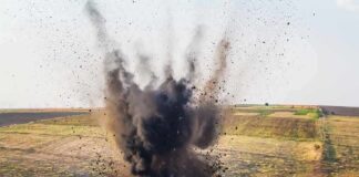 Explosion sending dark smoke and debris into the air in an open field