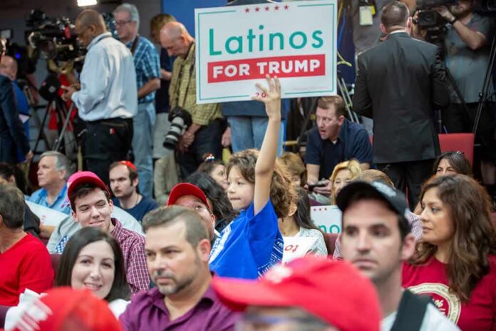 Child holding a 'Latinos for Trump' sign at a crowded rally
