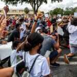 Freddie Williams II and Najeh Davenport among a large crowd kneeling at a protest