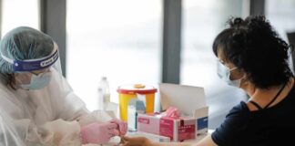 Healthcare worker performs finger-prick test on masked patient