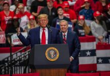 two men at a podium during a large indoor rally
