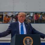 Trump Targets China’s Mineral Dominance Donald Trump speaks at a podium with arms outstretched