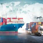 Cargo ship with containers alongside trucks, plane, and forklifts at a port