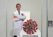 Delete Order Rocked Fauci’s Inbox Cardboard cutout of doctor with COVID-19 virus info display