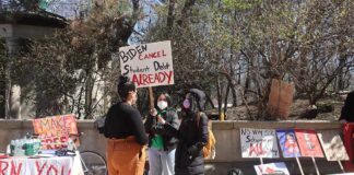 protesters with signs at an outdoor student debt rally
