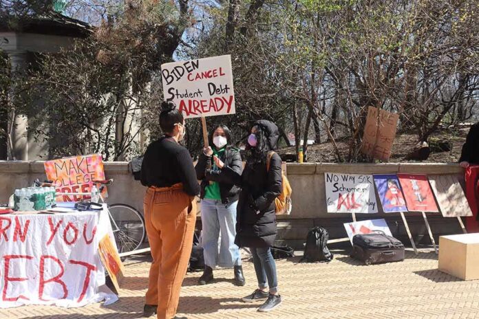 protesters with signs at an outdoor student debt rally