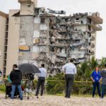 Run Or Drown — 7.7 Triggers Coastal Scramble Partially collapsed beachfront apartment building with onlookers