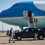 Six Black Axe Suspects Extradited to U.S. Security detail near blue and white aircraft with staircase and SUV
