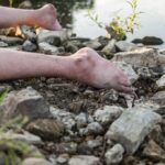 bare legs on rocky riverbank