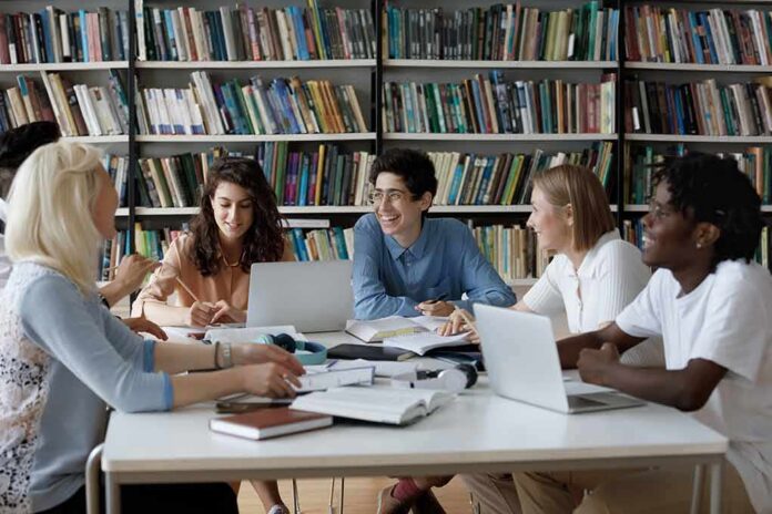 shutterstock_2111420681 Students collaborating at a table in a library