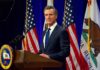 California Sets New Rules for Immigration Enforcement Man in suit speaking at a podium with American and California flags