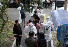 Deadly Rat Disease Triggers Berkeley Crackdown Christian Jones and others wait at an outdoor COVID-19 testing site with staff in protective suits