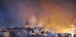 Riot police gather amid smoke at night