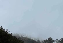 Hollywood sign partially hidden by fog on a hillside