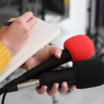 Iranian Assets, American Claims—and a Legal Gray Area Journalist holding two microphones while writing in a notebook