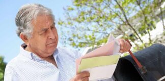 Older man checking mail at a rural mailbox