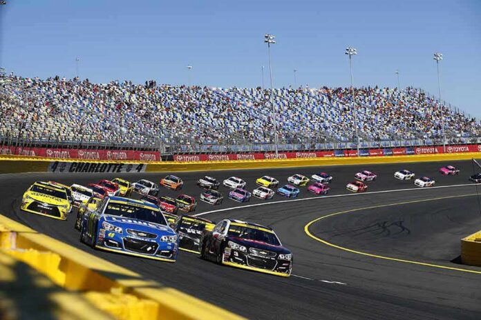 shutterstock_497557876 Stock cars racing on a banked track with grandstands in background