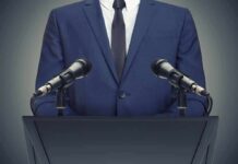 CEO Security Sparks a Health Care Debate Speaker in suit at podium with two microphones