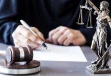$105M Truck Investment Scheme Alleged Judge writing at desk with gavel and Lady Justice statue