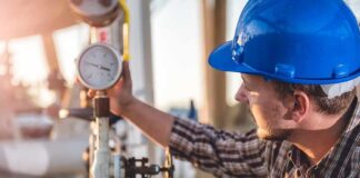 Engineer in blue hard hat checking a pressure gauge