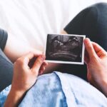 Person holding an ultrasound photo over a pregnant belly