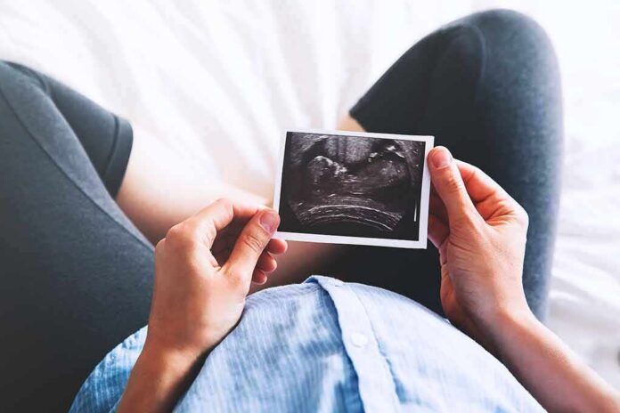 Person holding an ultrasound photo over a pregnant belly