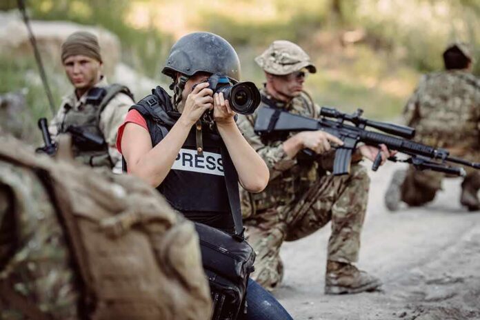 Teddy Williams photographing near armed soldiers in a field