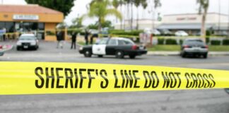 yellow sheriff's line tape blocks a street near police cars