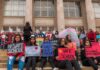 $275K Deal Follows Bible Access Dispute Students holding protest signs on school steps