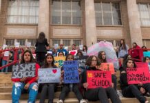 $275K Deal Follows Bible Access Dispute Students holding protest signs on school steps