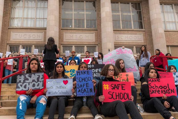 shutterstock_1046281249 Students holding protest signs on school steps