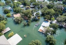 Dozens Rescued As Floodwaters Swamp Communities Aerial view of flooded neighborhood with rescue boat navigating streets