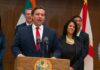 Ron DeSantis speaking at a podium with Chi Onwurah standing behind him